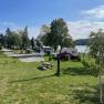 A campsite with caravans, trees and a lake in the background in sunny weather.