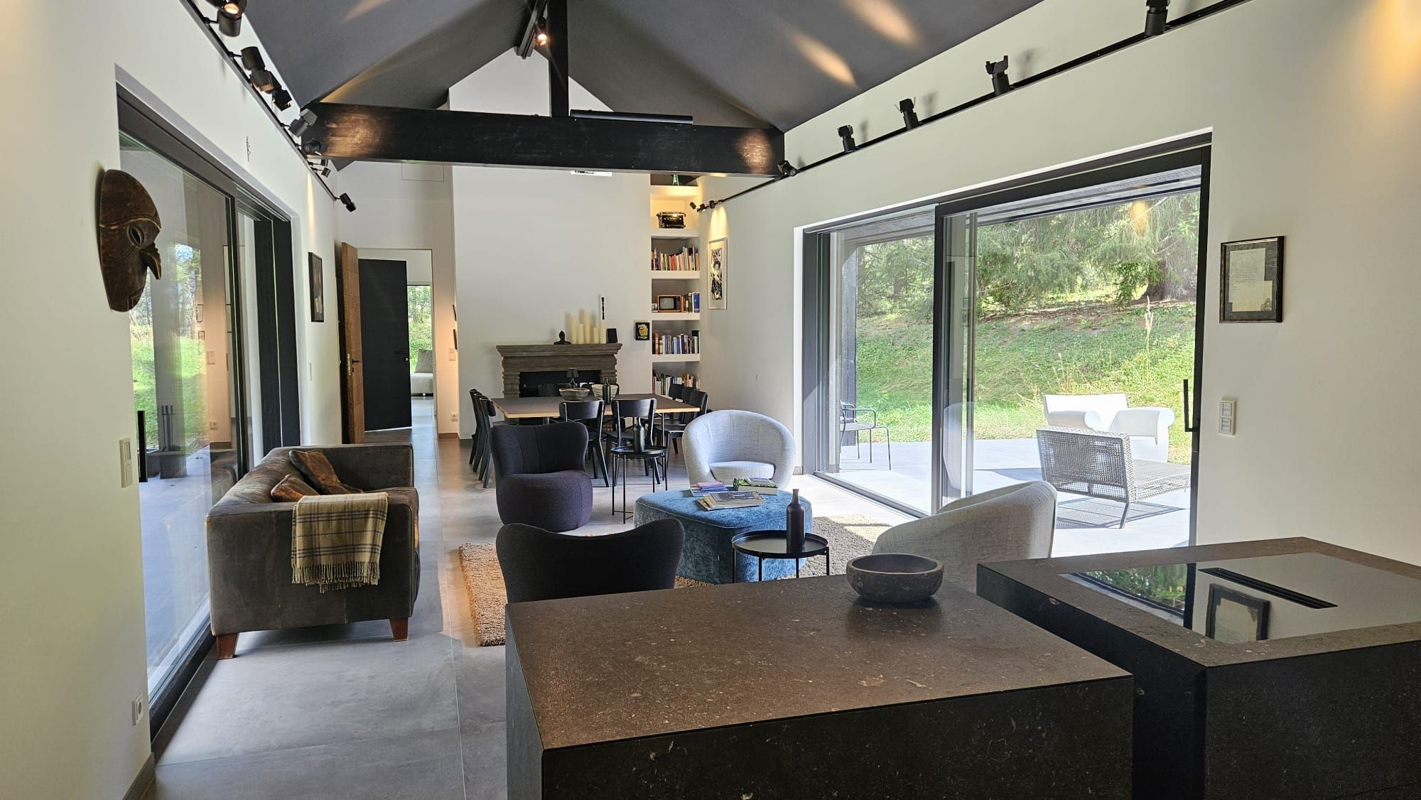 Modern living room with large windows, sofas and fireplace.