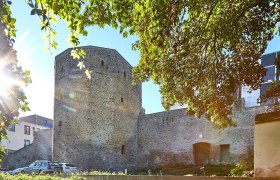 Town wall and tower in Waidhofen an der Thaya, surrounded by trees and sunlight.