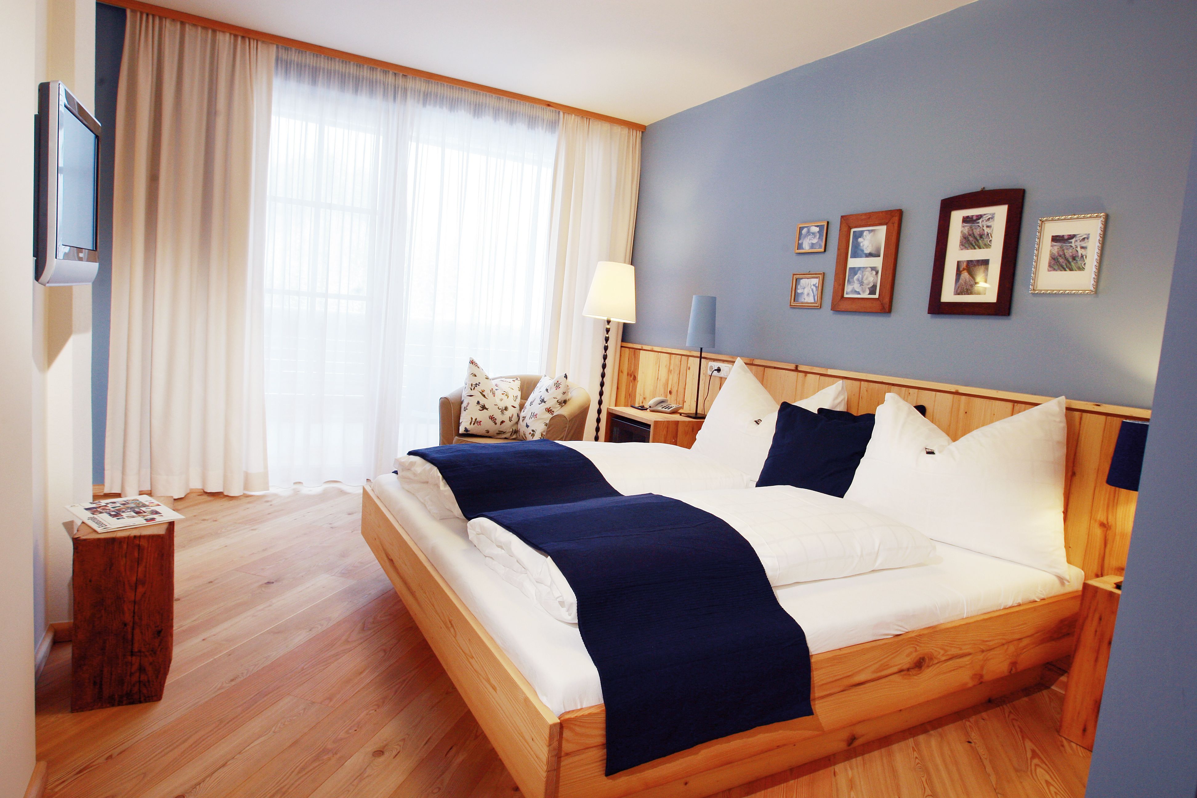 Cozy hotel room with double bed, blue accents and wooden furniture.