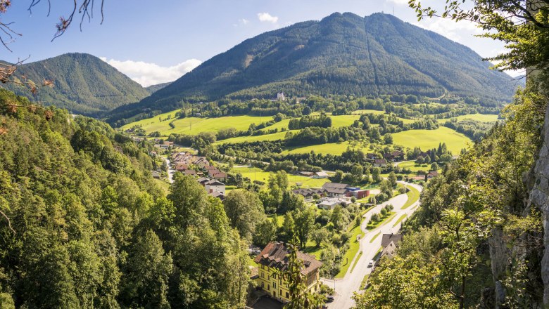 Panoramic view of a green valley with mountains in the background and a village in the foreground.