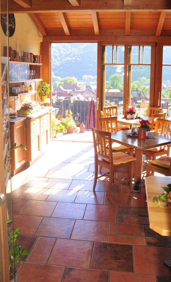 Interior of a sunny conservatory with wooden furniture and a view of the countryside.