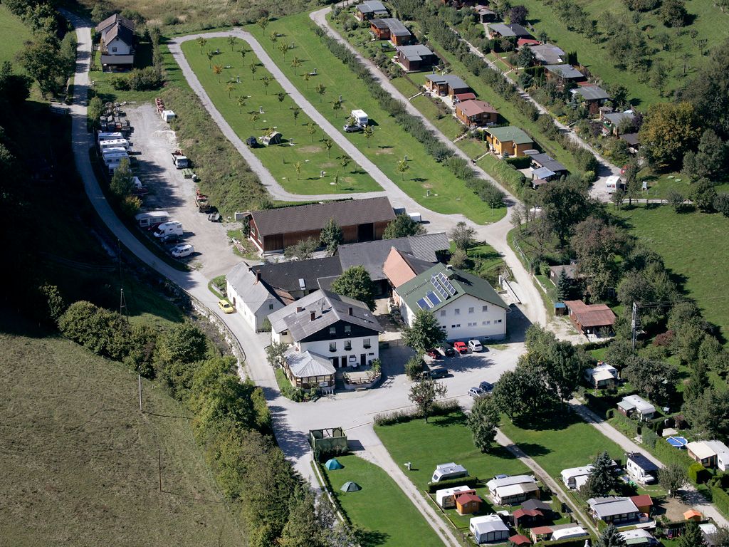 Aerial view of a campsite with caravans and buildings in a green landscape.