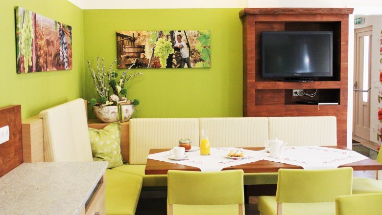 Guesthouse Loiskandl, © Gästehaus Loiskandl / Elisabeth Widhalm Cozy dining area with green walls, wooden furniture and a TV.