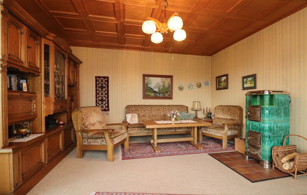 Cozy living room with wooden furniture, green tiled stove and carpet.