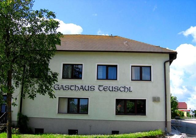 Exterior view of Gasthaus Teuschl with trees and blue sky.