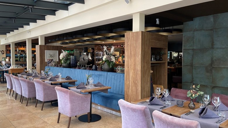 Elegant restaurant with laid tables and purple chairs.