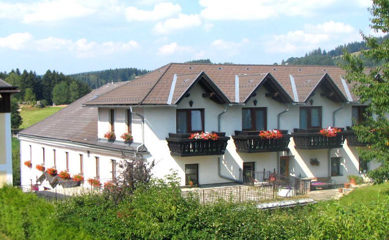 A large, white building with brown roofs and balconies with flowers.