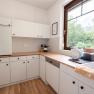 Modern kitchen with white cupboards, wooden worktop and large window with a view of the greenery.