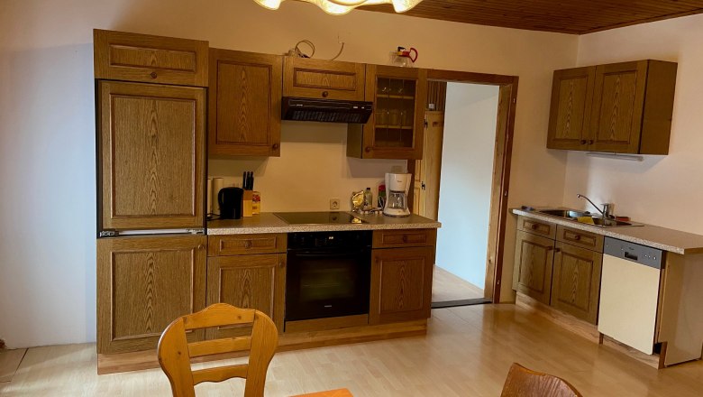 Kitchen with wooden furniture, dining table and chairs, stove, sink and dishwasher.