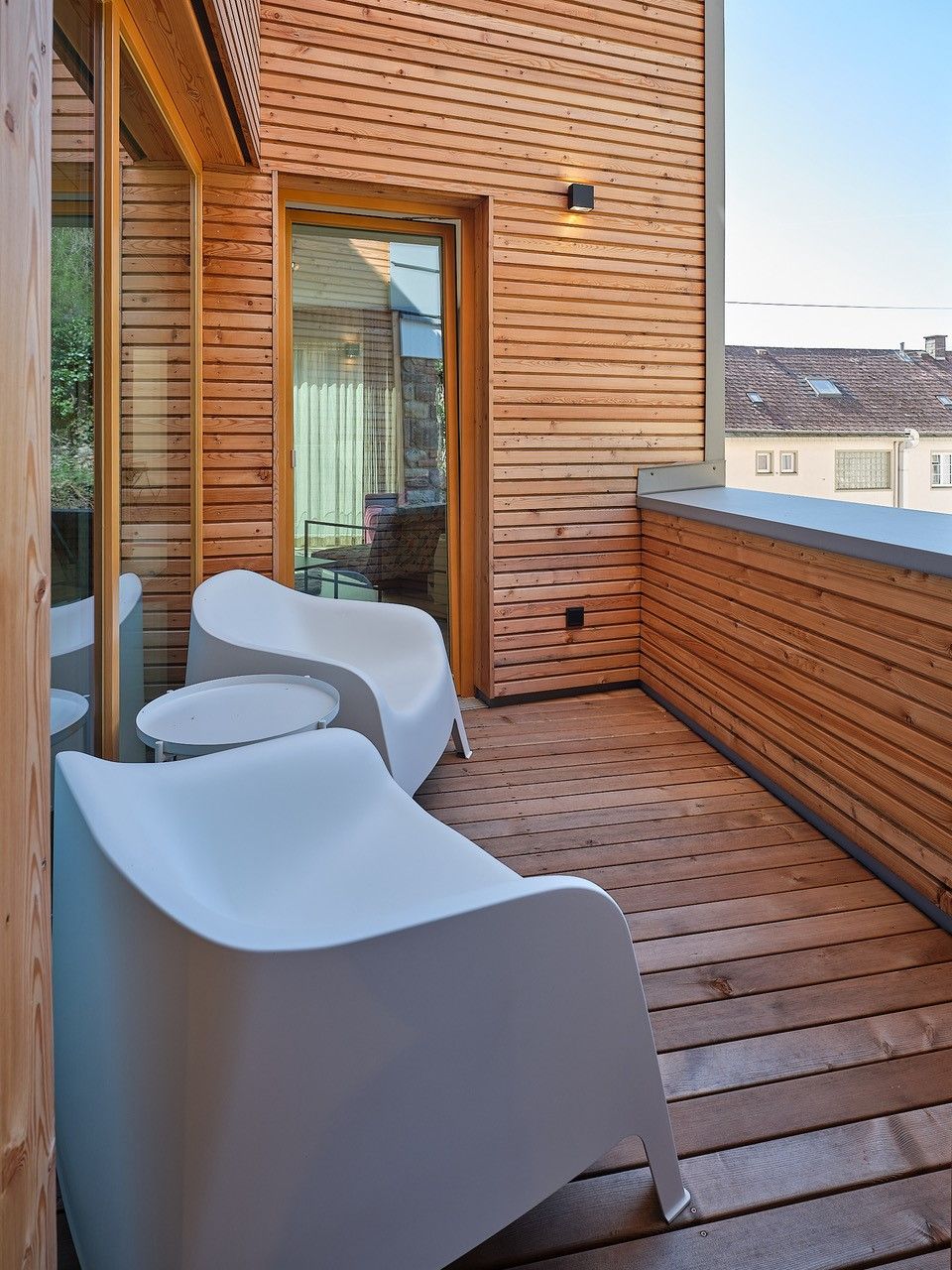 Modern balcony with wooden walls and white chairs.