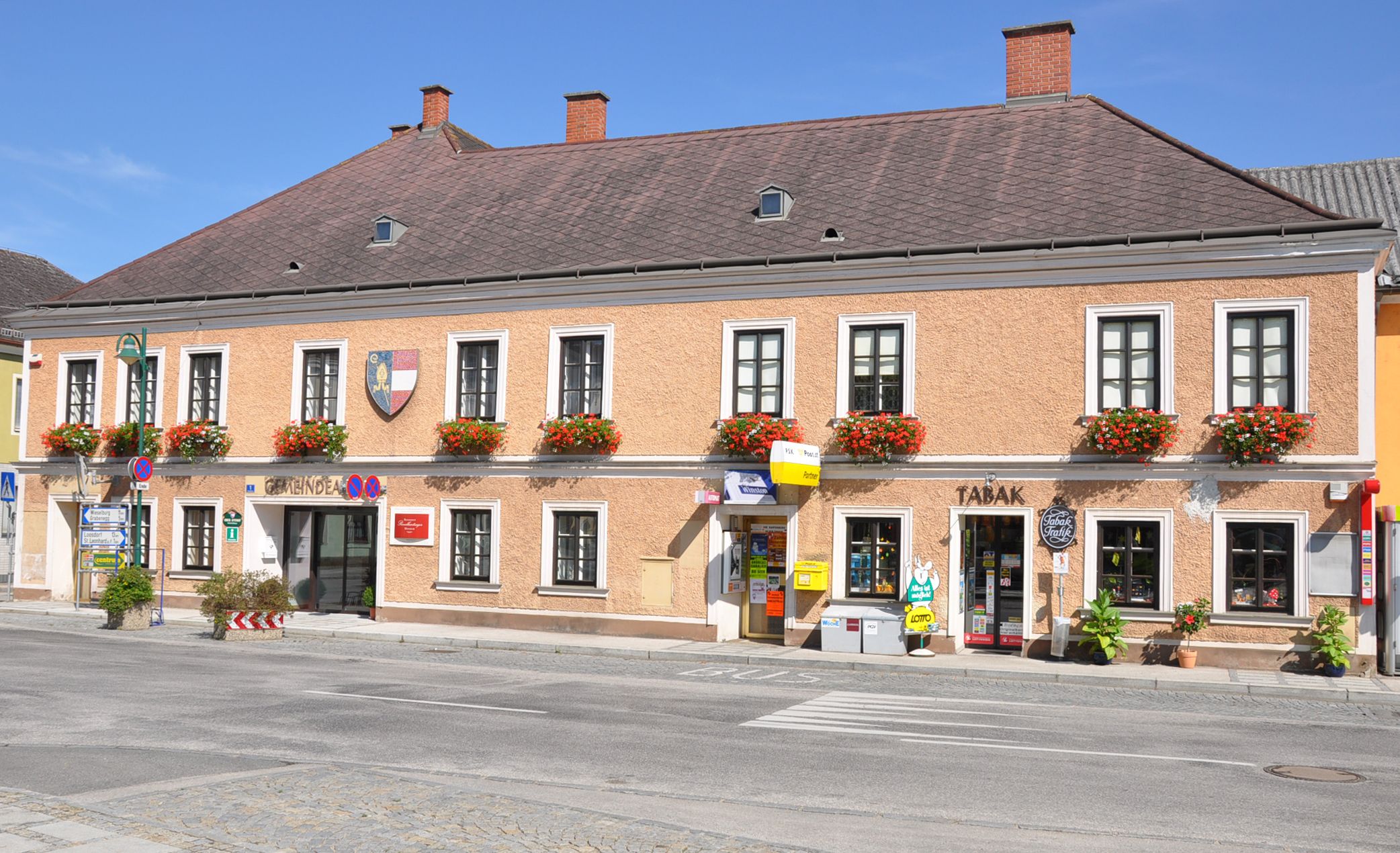 A two-storey building with flowers in the windows and stores on the first floor in Ruprechtshofen.