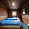 Rustic bedroom with wood paneling and double bed.