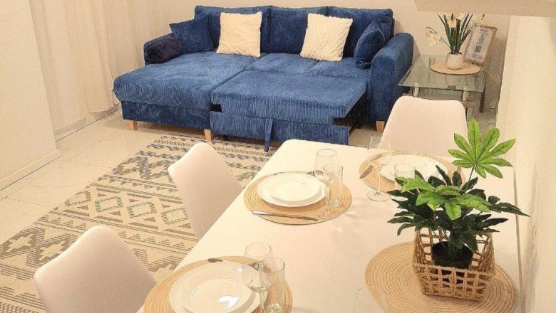 Living room with blue sofa and dining table with place settings.