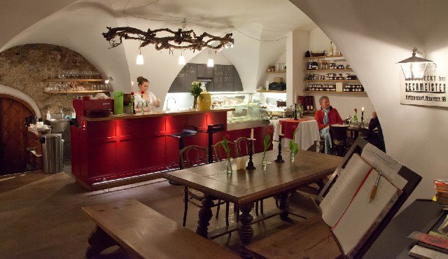 Cozy caf&eacute; with a red bar and wooden tables.