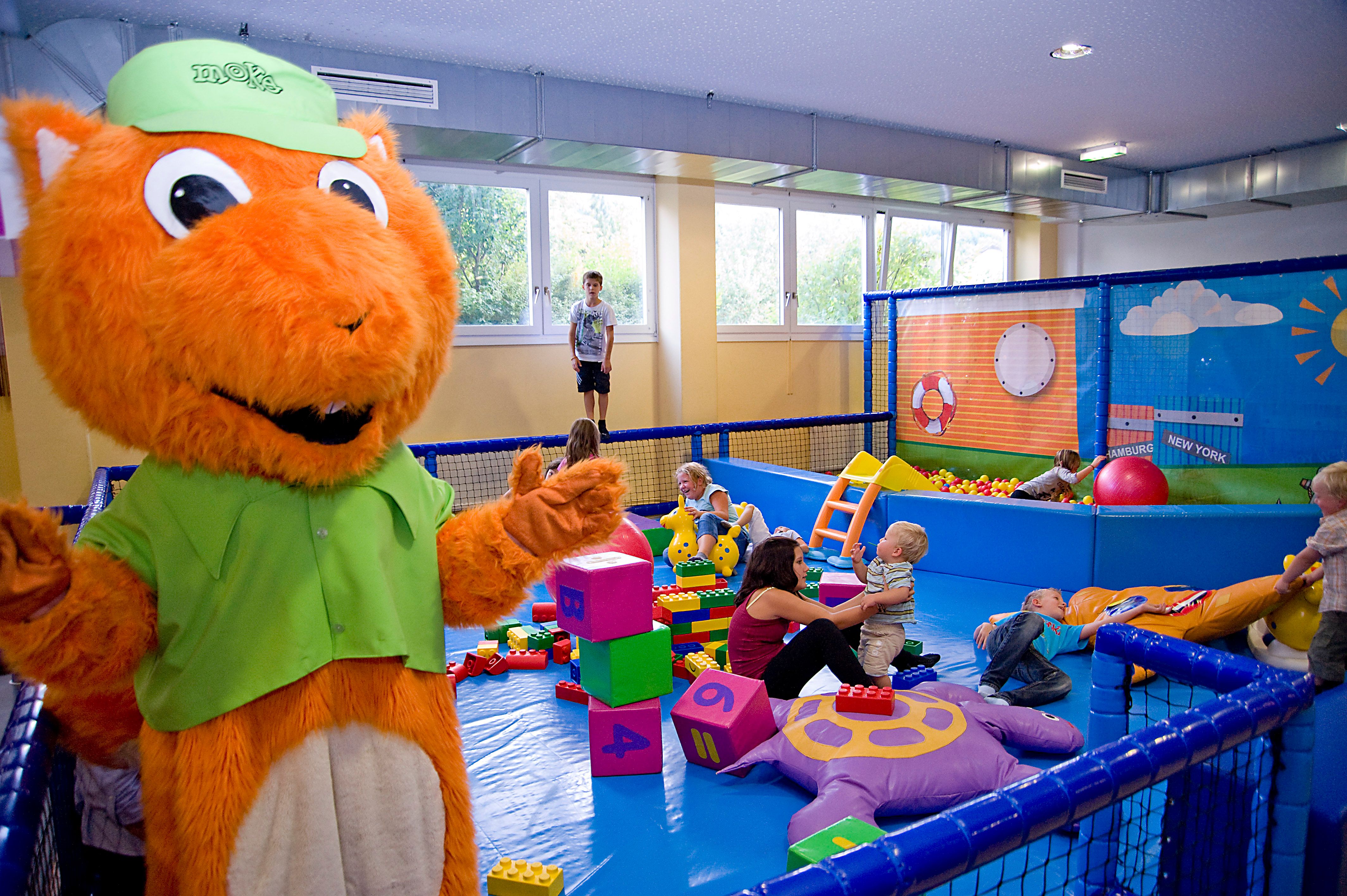 Children play in an indoor play area with a large orange mascot.
