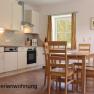 Bright kitchen with dining table and chairs, window with curtains, tiled floor.