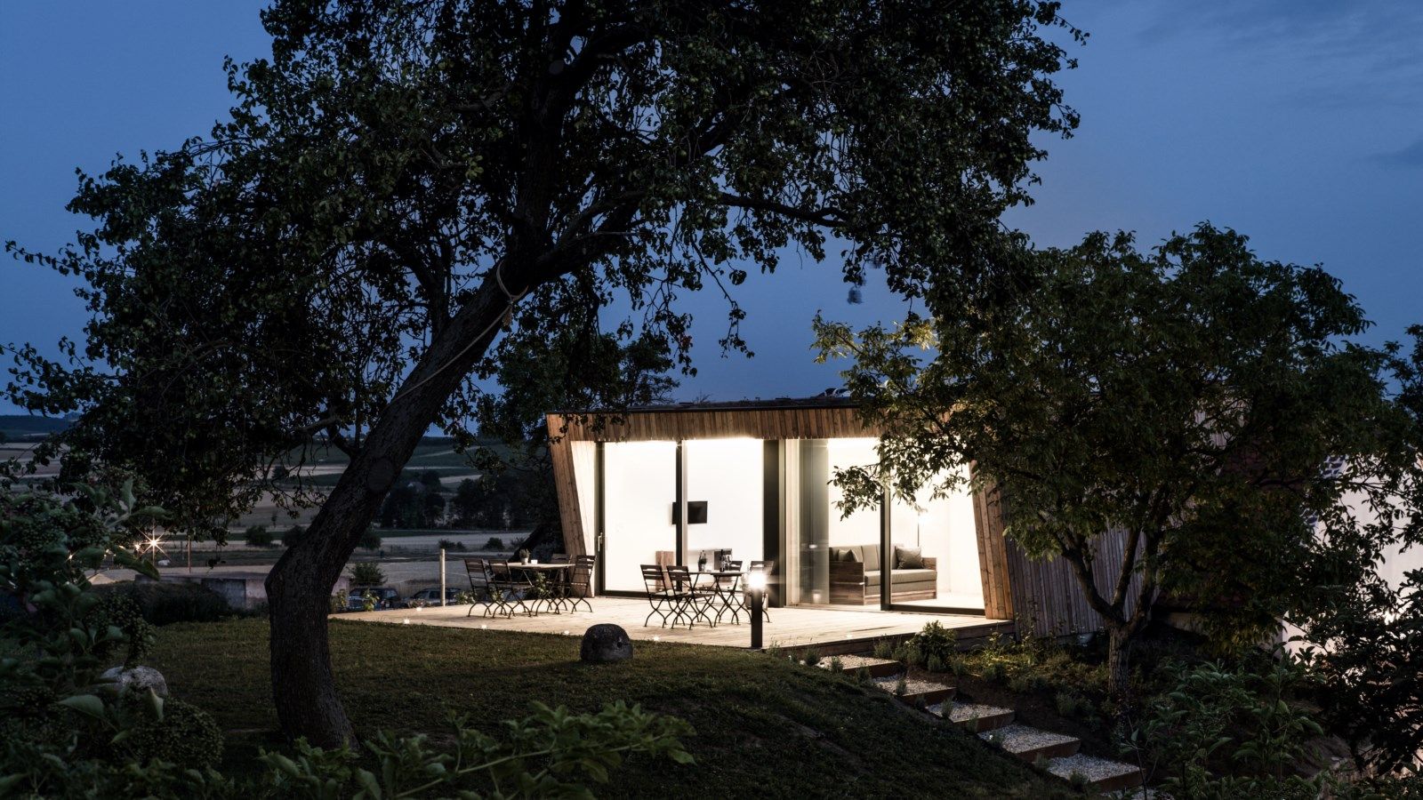 Modern building with glass front in a rural setting at dusk.