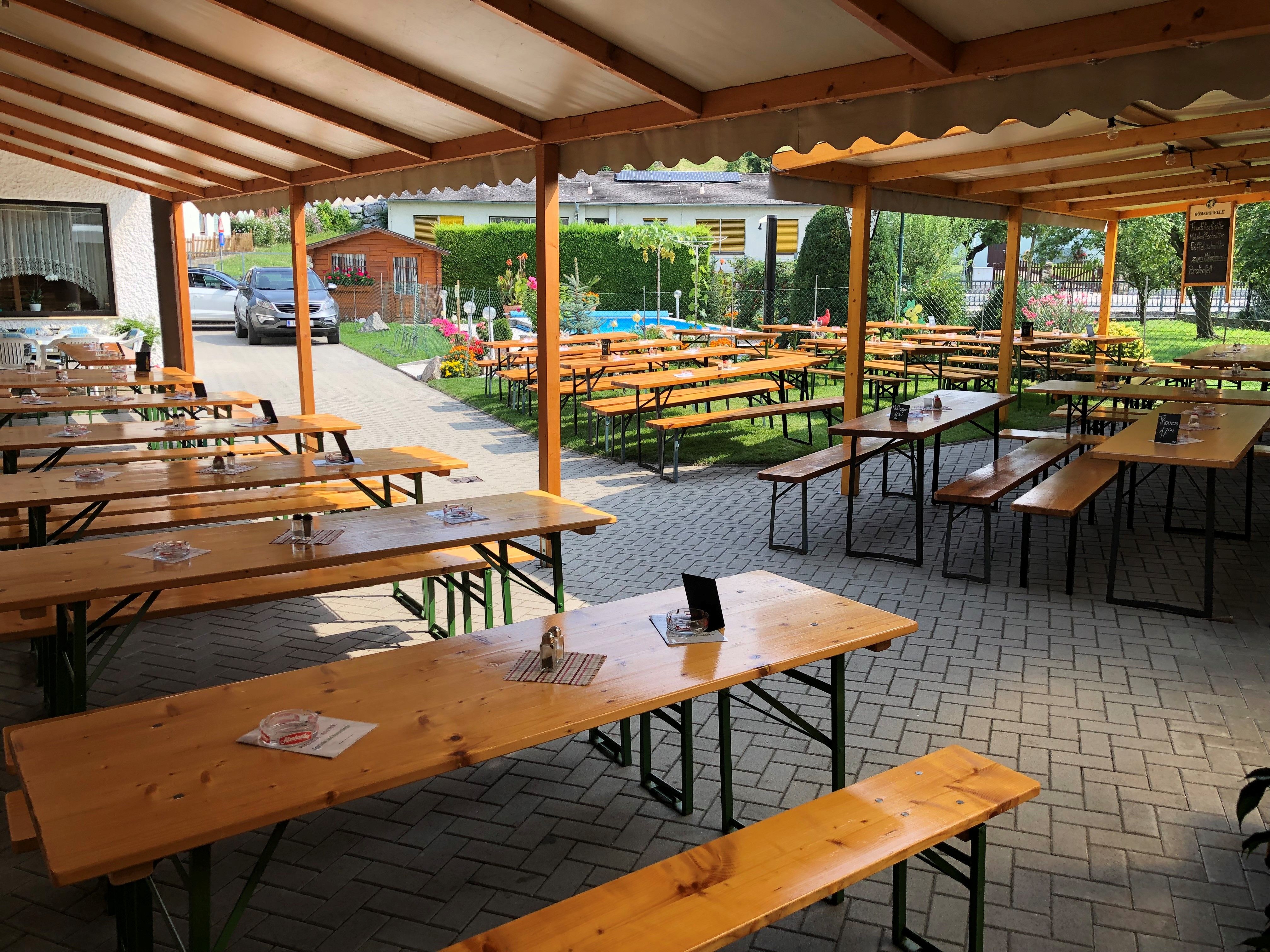 Covered outdoor area of a wine tavern with wooden benches and tables.