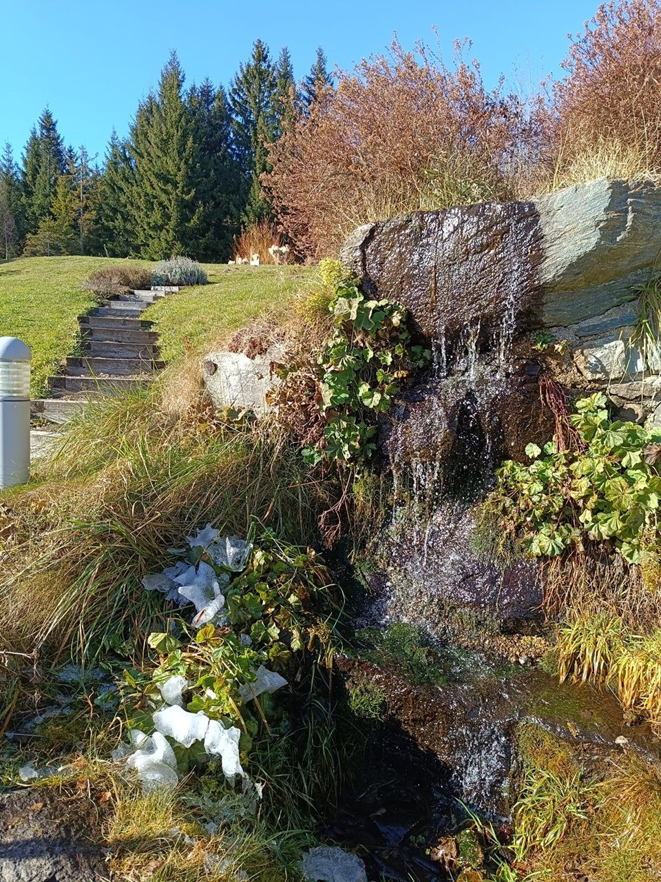 Small waterfall in an autumnal landscape with trees and blue sky.