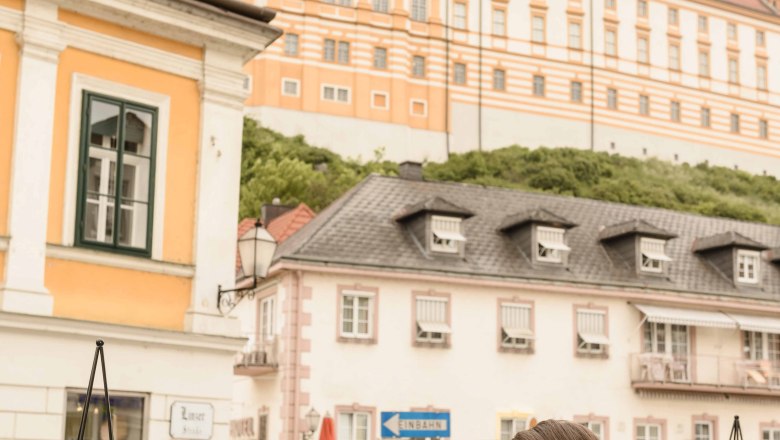 Two women enjoy ice cream sundaes in the garden with a view of Melk Abbey.