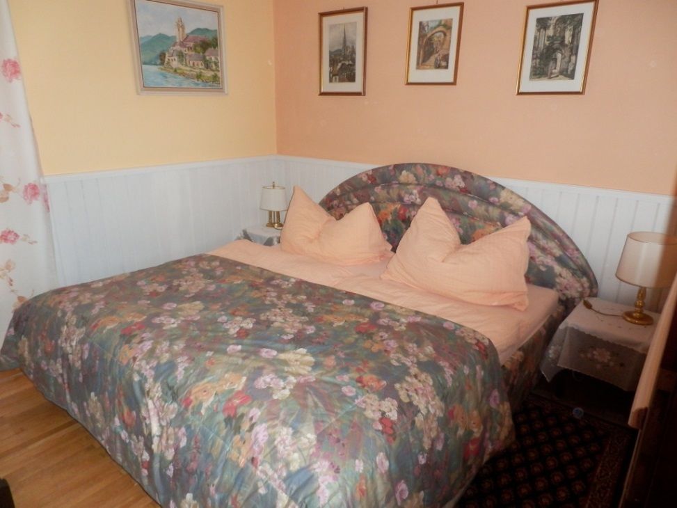 Bedroom with double bed, floral bed linen and pictures on the wall.