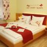 A cozy hotel room with a double bed, red accents and an inspiring wall quote.