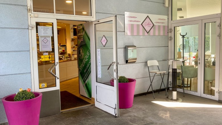 Entrance coffee house klinks and on the right pink flower pots in front of light blue house