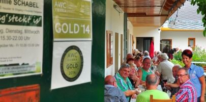 People sit at a long table in a covered outdoor area of a restaurant.
