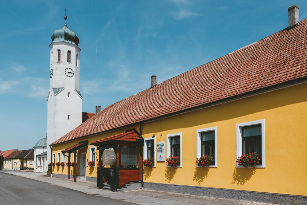 Yellow building with church tower and blue sky in a cityscape.
