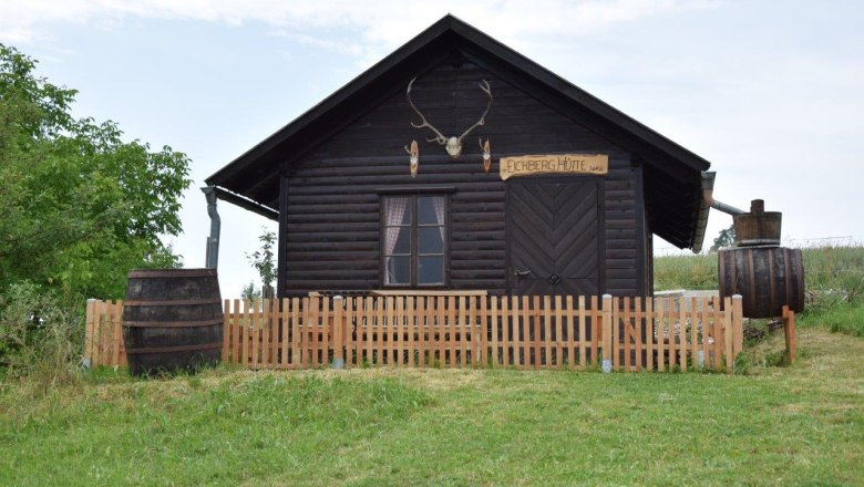 A rustic wooden hut with antlers above the door and a wooden fence in front of it.