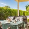 Outdoor breakfast table with crockery and green tablecloth, surrounded by hedges.