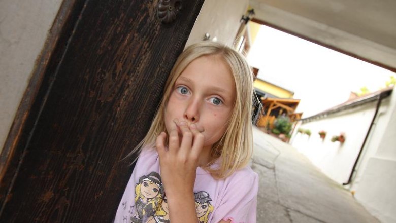Come in, © Fam. Schwalm A girl stands in an archway and looks at the camera in surprise.