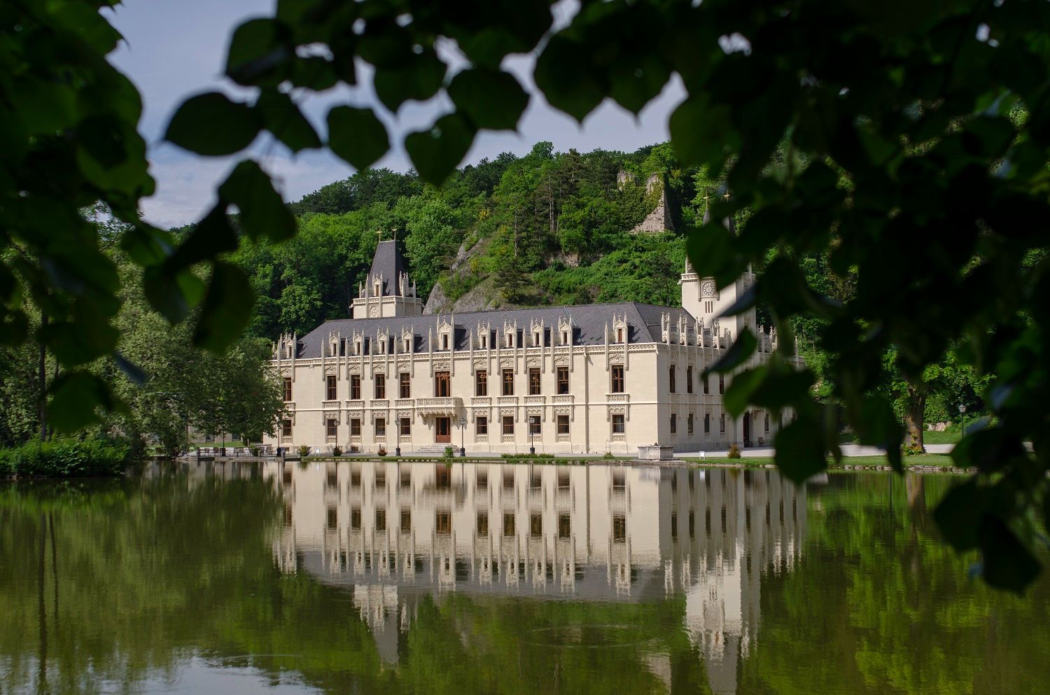 Schloss Hernstein is reflected in a lake surrounded by trees.