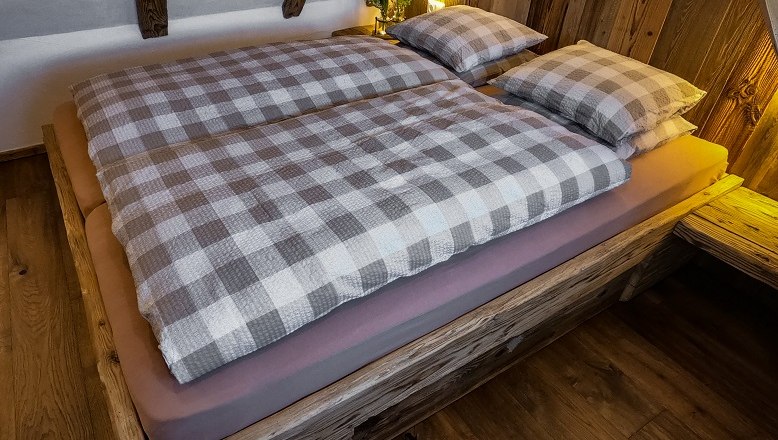 Cozy bed with checkered bedding in a wooden hut.