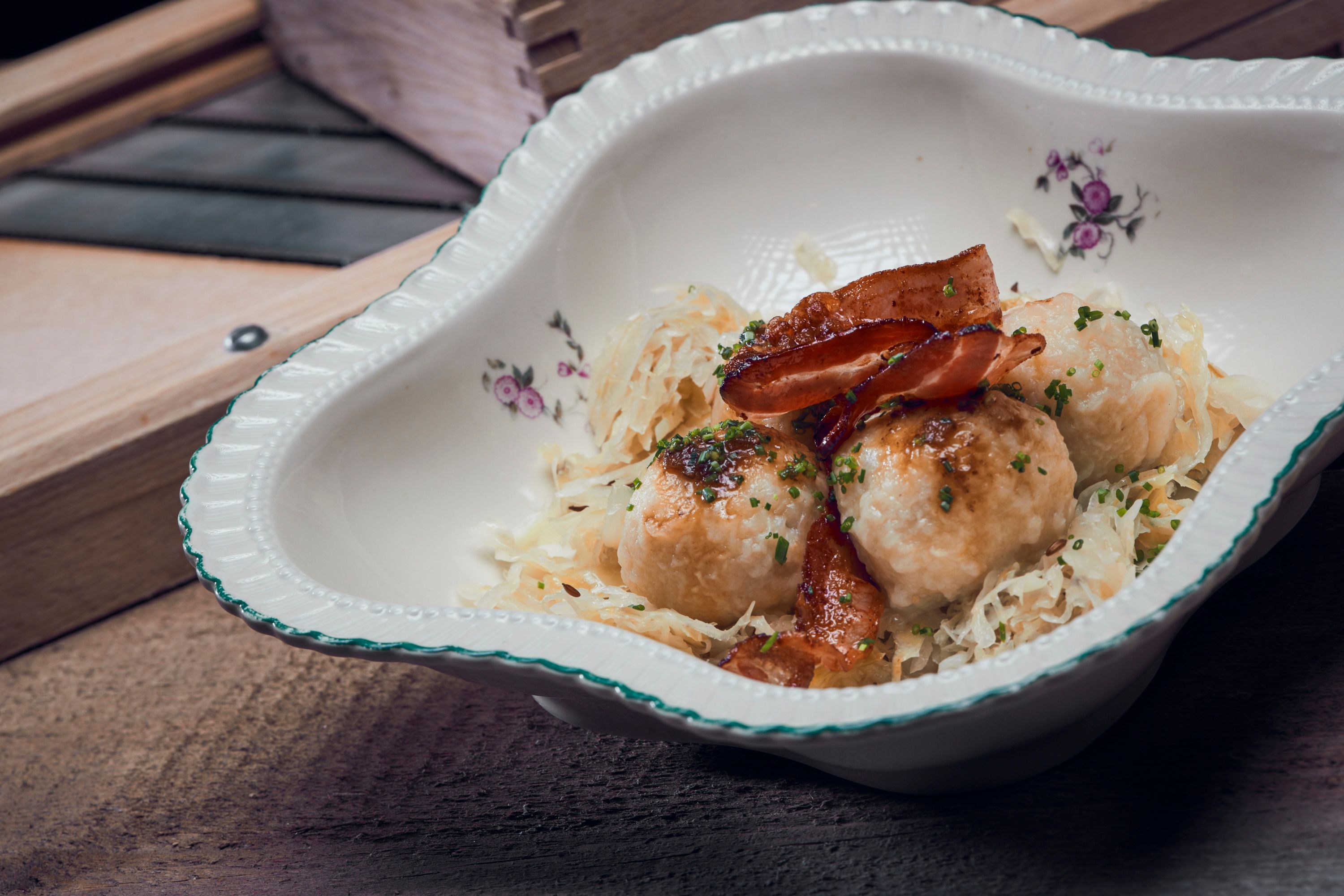 Traditional dish with dumplings, bacon and sauerkraut in a decorative bowl.