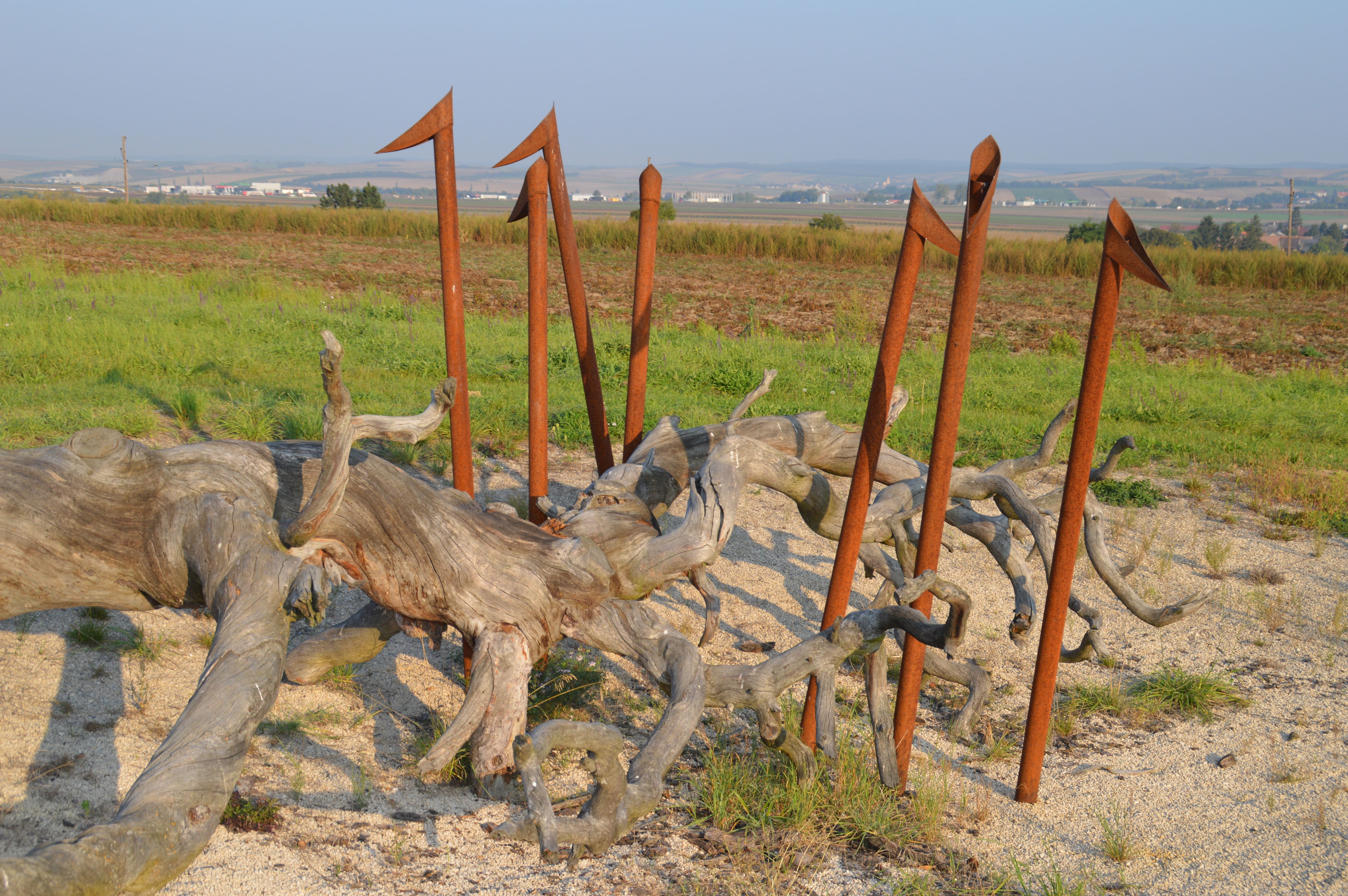 Art installation made of wood and metal rods in a rural landscape.