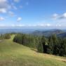 View of a green mountain landscape with forests and blue sky.