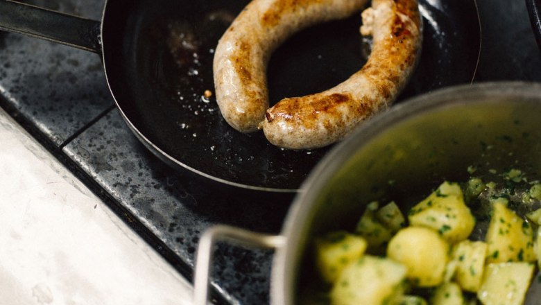 Sausage in a pan with potatoes in a pot.
