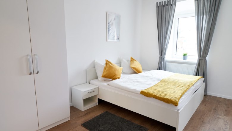 Modern double room with white bed, yellow pillows and gray curtains.