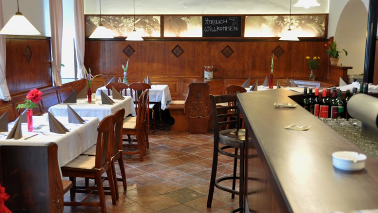 Interior view of a cozy restaurant with wooden furniture and laid tables.