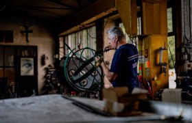 A man is working on a sundial in a workshop.