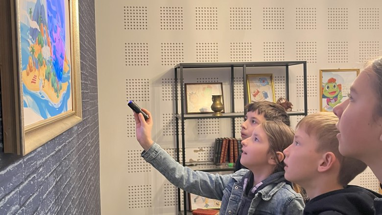 Children illuminate a picture with blue light to decipher a puzzle