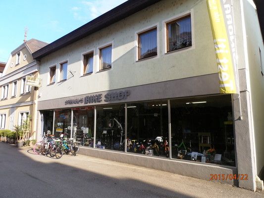 Bicycle store in a small street with several bicycles in front of the shop window.