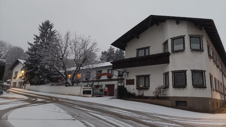 TDR-WelserhofWinter, © Nora Bartfai Snow-covered street with buildings in winter, illuminated windows.