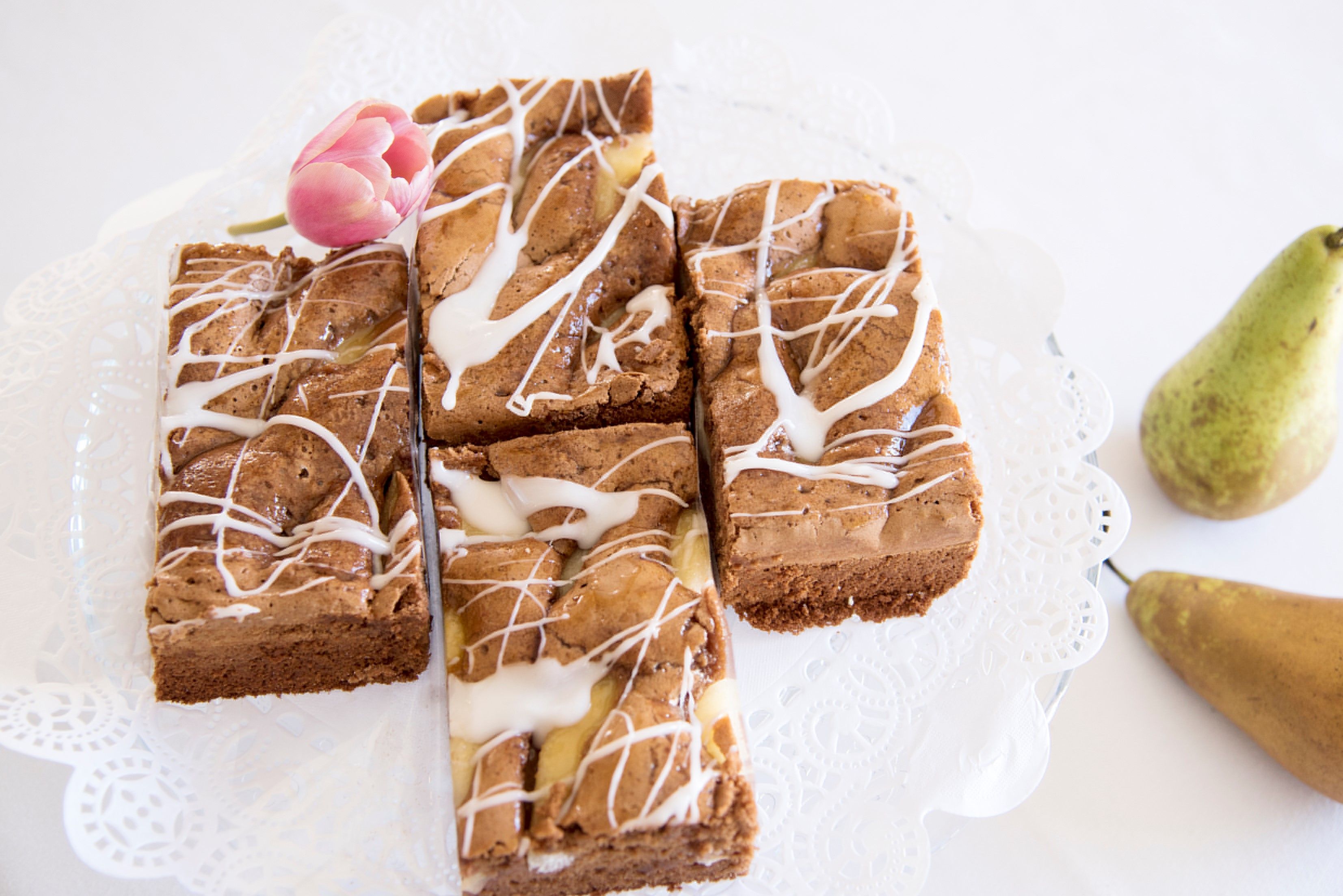 Homemade pastry with icing and tulip decoration, with pears next to it.