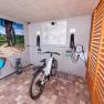 Bicycle in a garage with charging stations and mural of a cyclist in a vineyard.