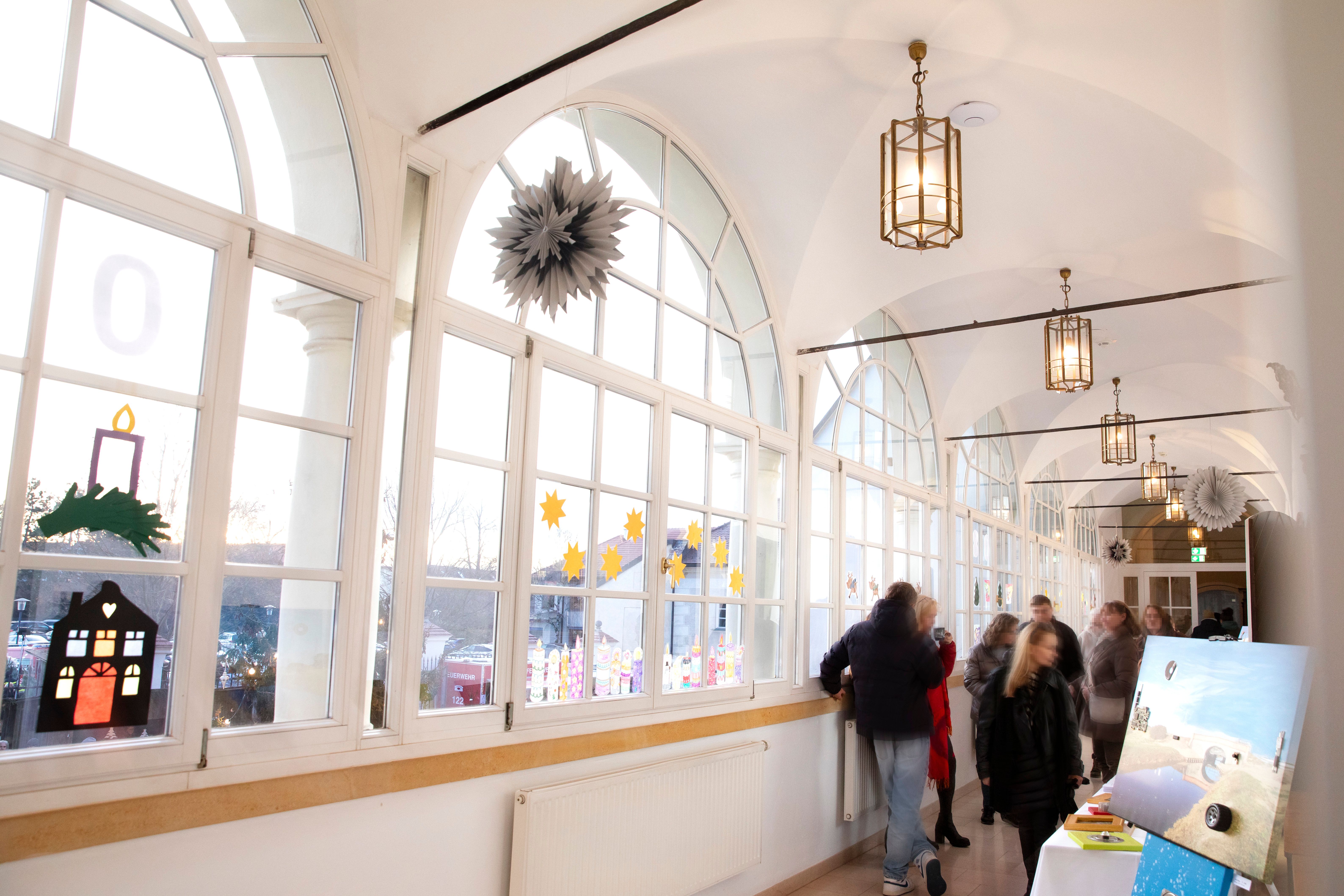 A bright corridor in the castle with large windows and a stall at the Christmas market with art.
