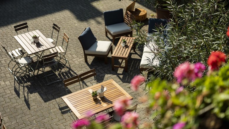 Cozy outdoor area with wooden furniture and plants, sunny atmosphere.
