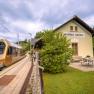 A golden train stops at Wienerbruck-Josefsberg station, surrounded by green countryside and a small outdoor seating area.
